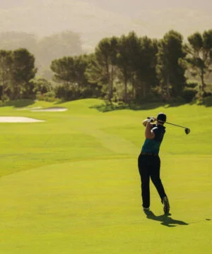 Man on a golf course on the follow-through of his golf swing